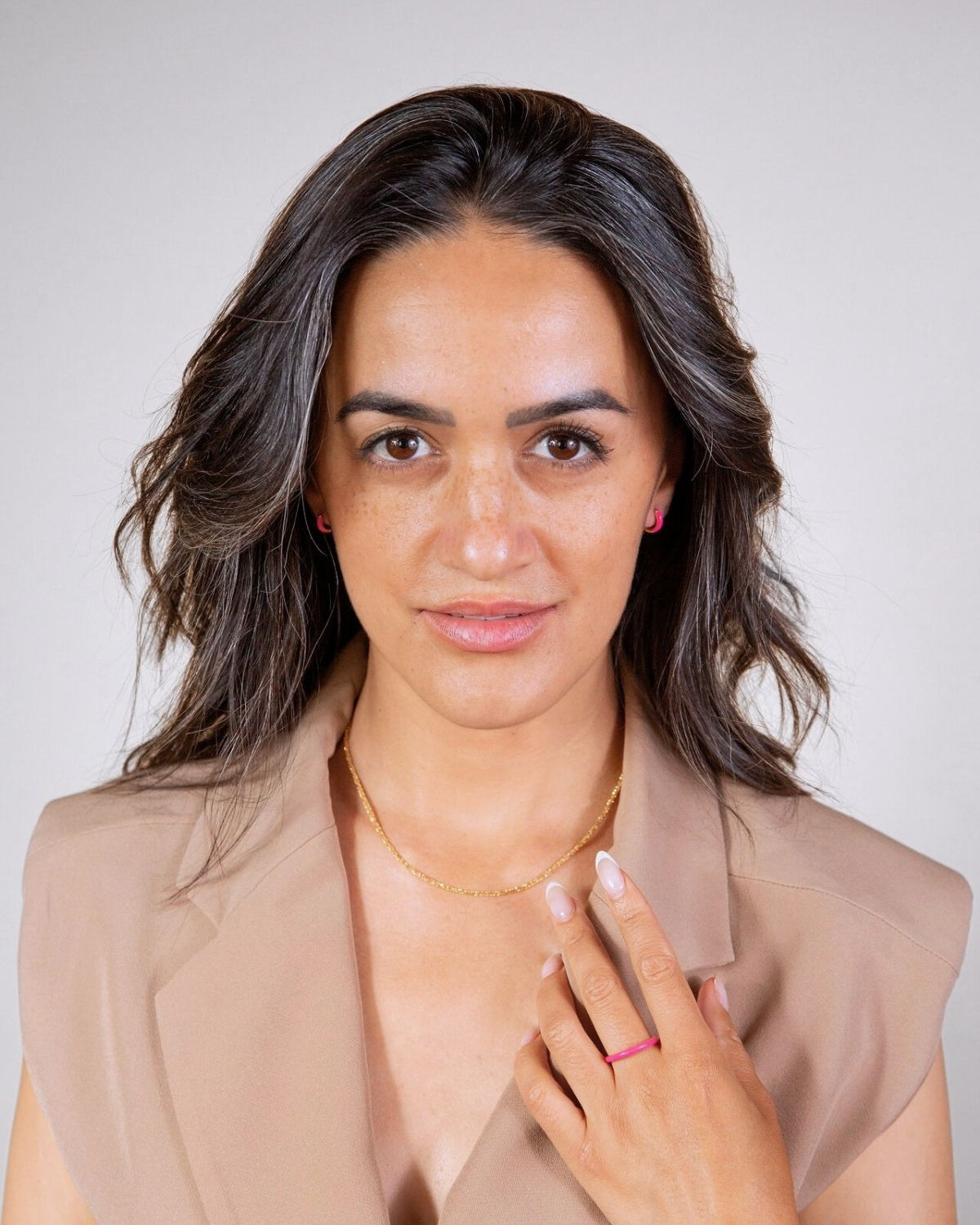 model wears pink enamel ring and pink enamel huggie hoop earrings