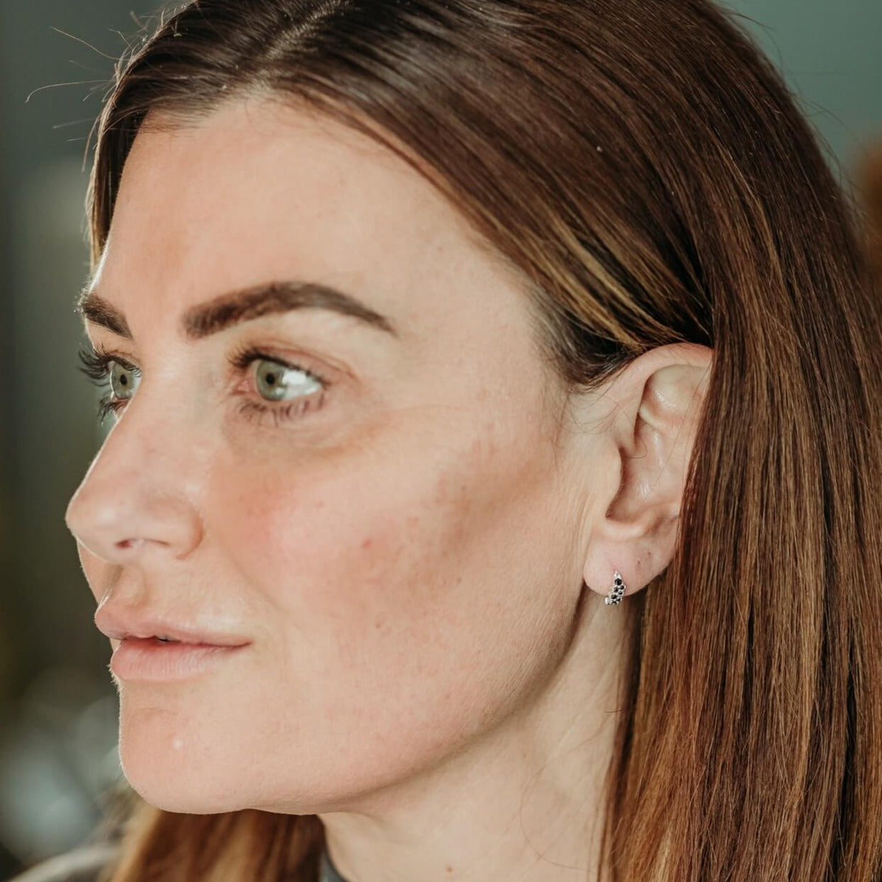 model wears black cubic zirconia and silver huggie hoop earrings