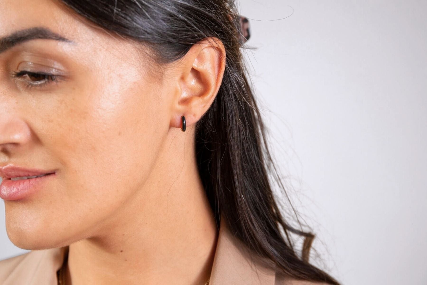 model wears Black Enamel Gold Huggie Hoop Earrings