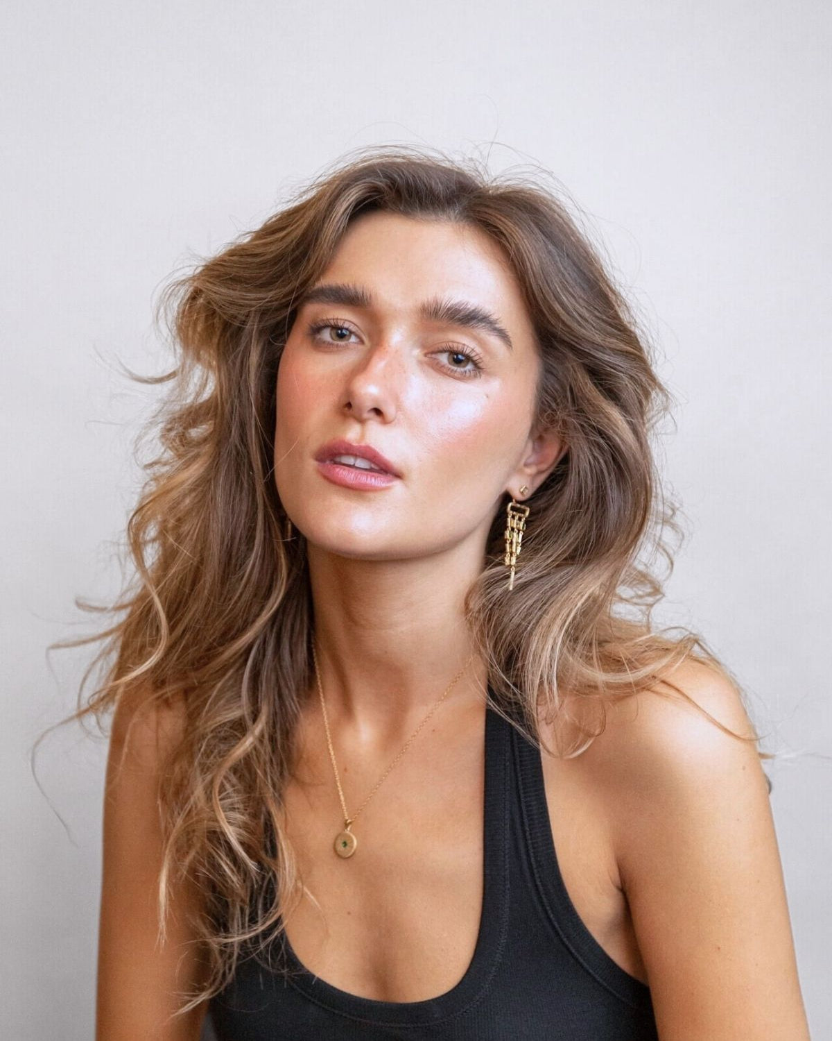 model wears emerald gold chandelier ear jacket earrings and gold lovespoon charm necklace