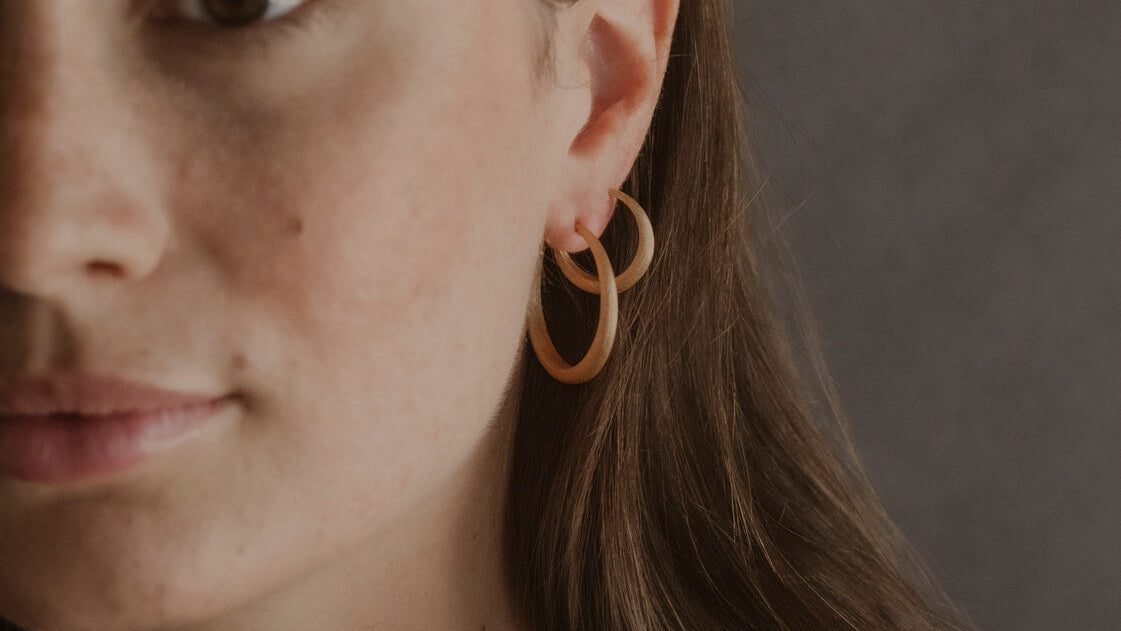 Model wears gold large and medium brushed hoops