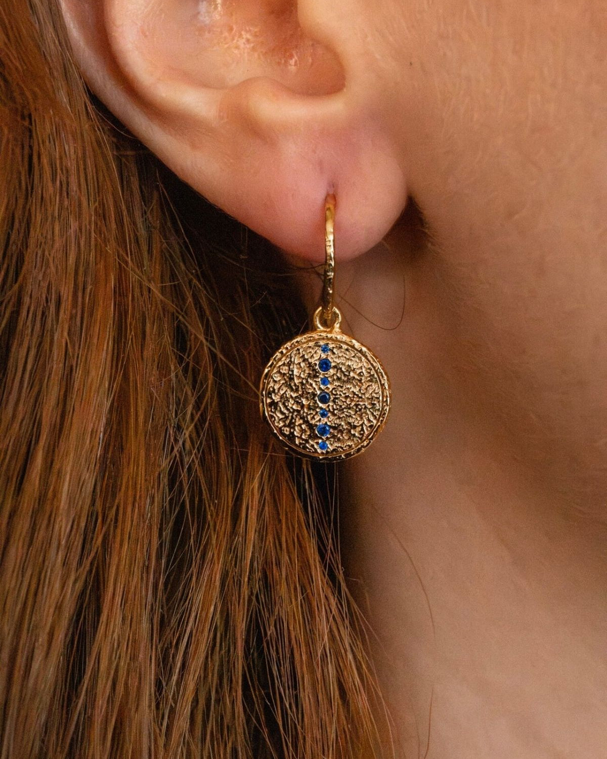 model wears sapphire gold coin drop earrings