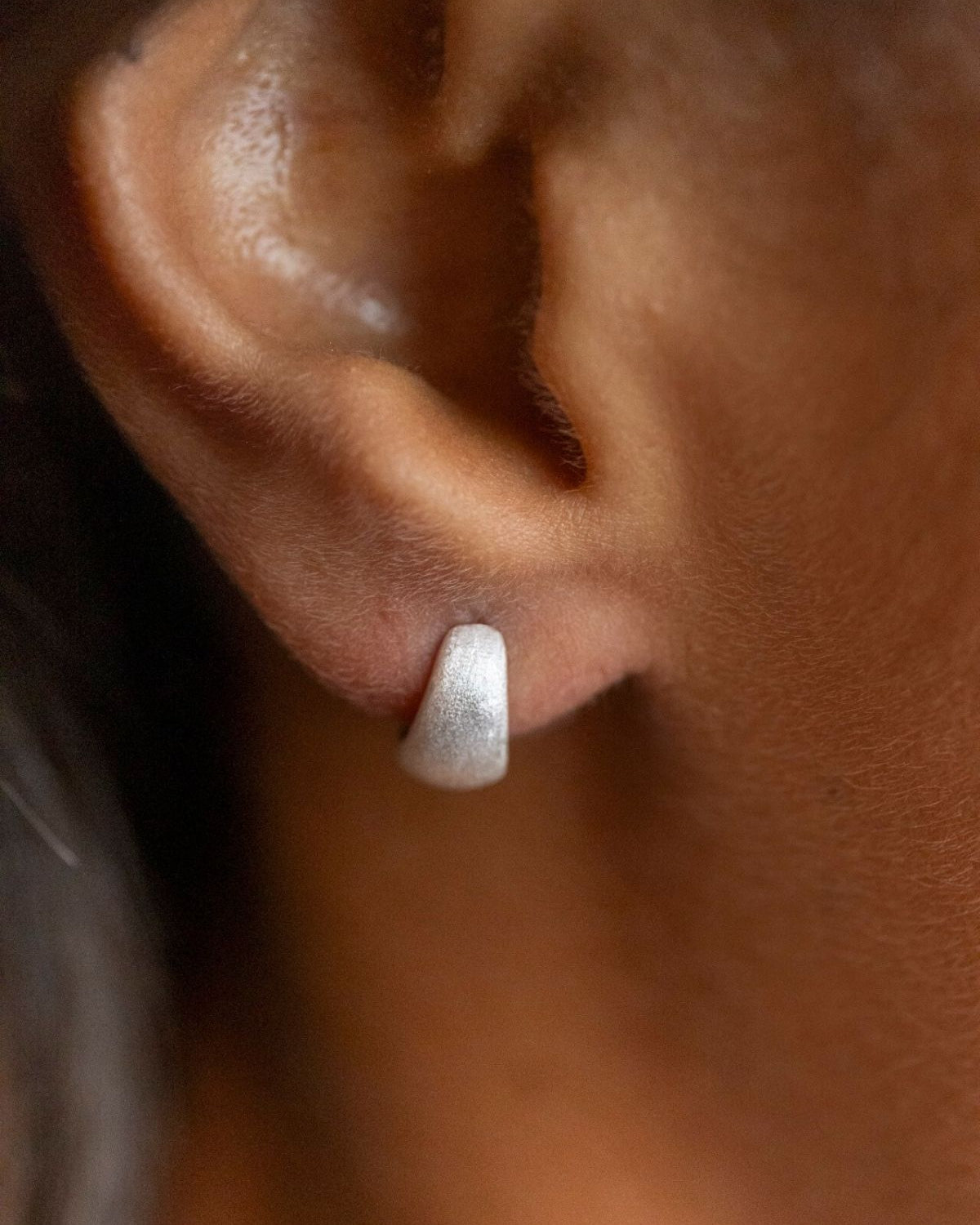 model wears Brushed Silver Chunky Huggie Hoops