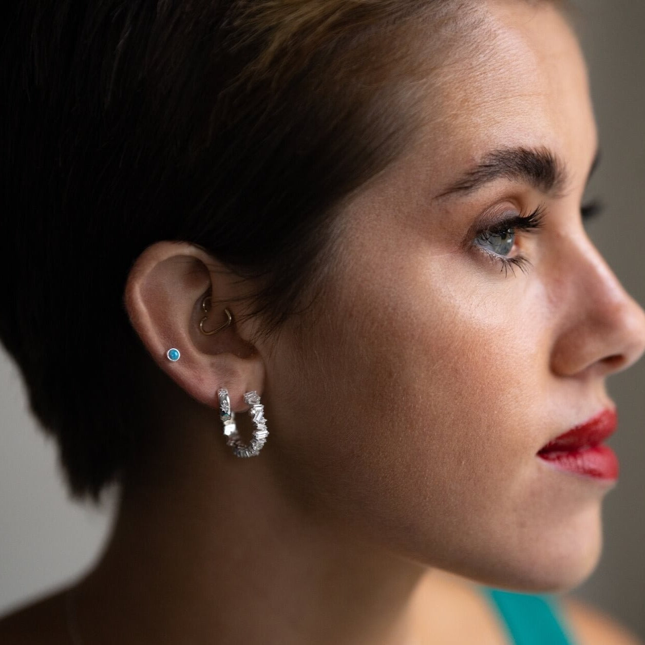 model wears ear stack of sparkly silver hoop earrings and silver and blue opal stud earring