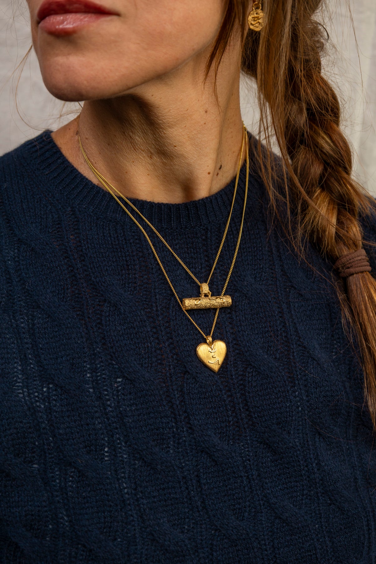 A close-up lifestyle shot of a woman wearing a gold T-bar pendant necklace with Difficult Woman and gold heart locket with Know Your Worth