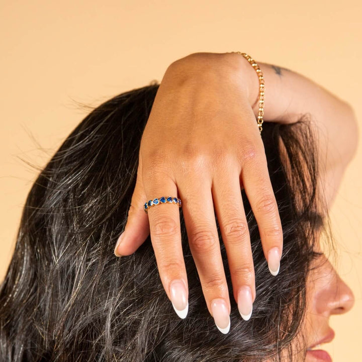 model wears 14k gold vermeil and blue cubic zirconia heart eternity ring
