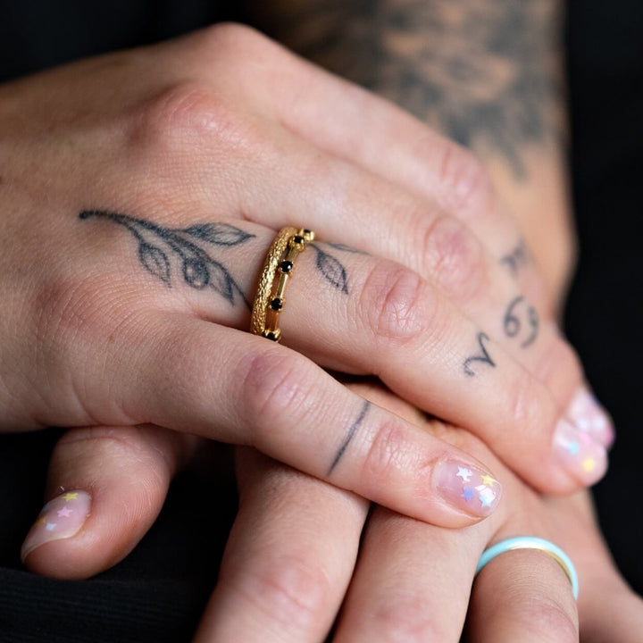 model wears 18k gold vermeil and black cubic zirconia studded dainty stacking ring and 18k gold vermeil antique textured stacking ring