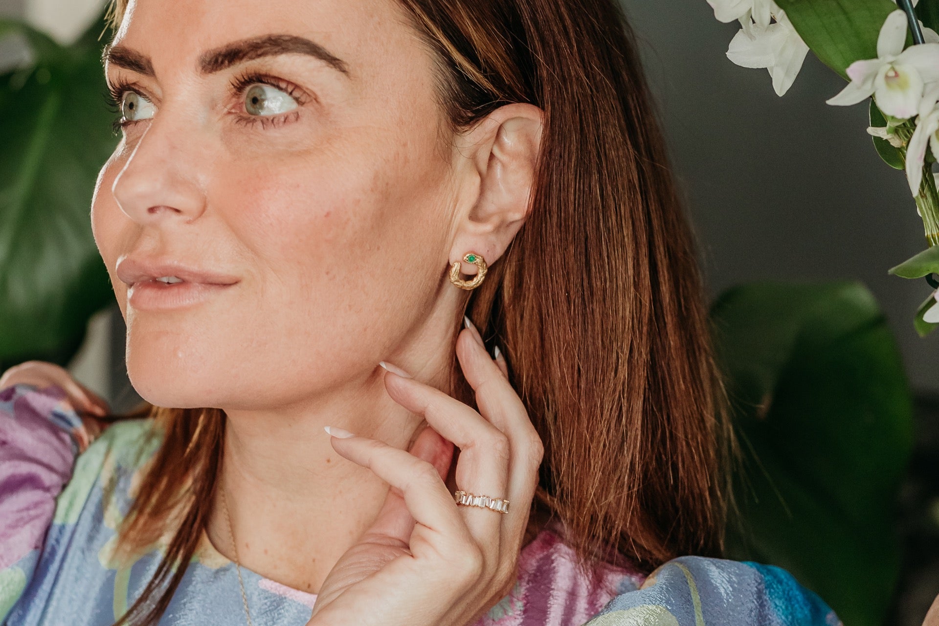model wears emerald gold asymetric stud earrings 

