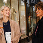 model eats croissant while wearing a model wears silver heart connector necklace and gold heart connector necklace