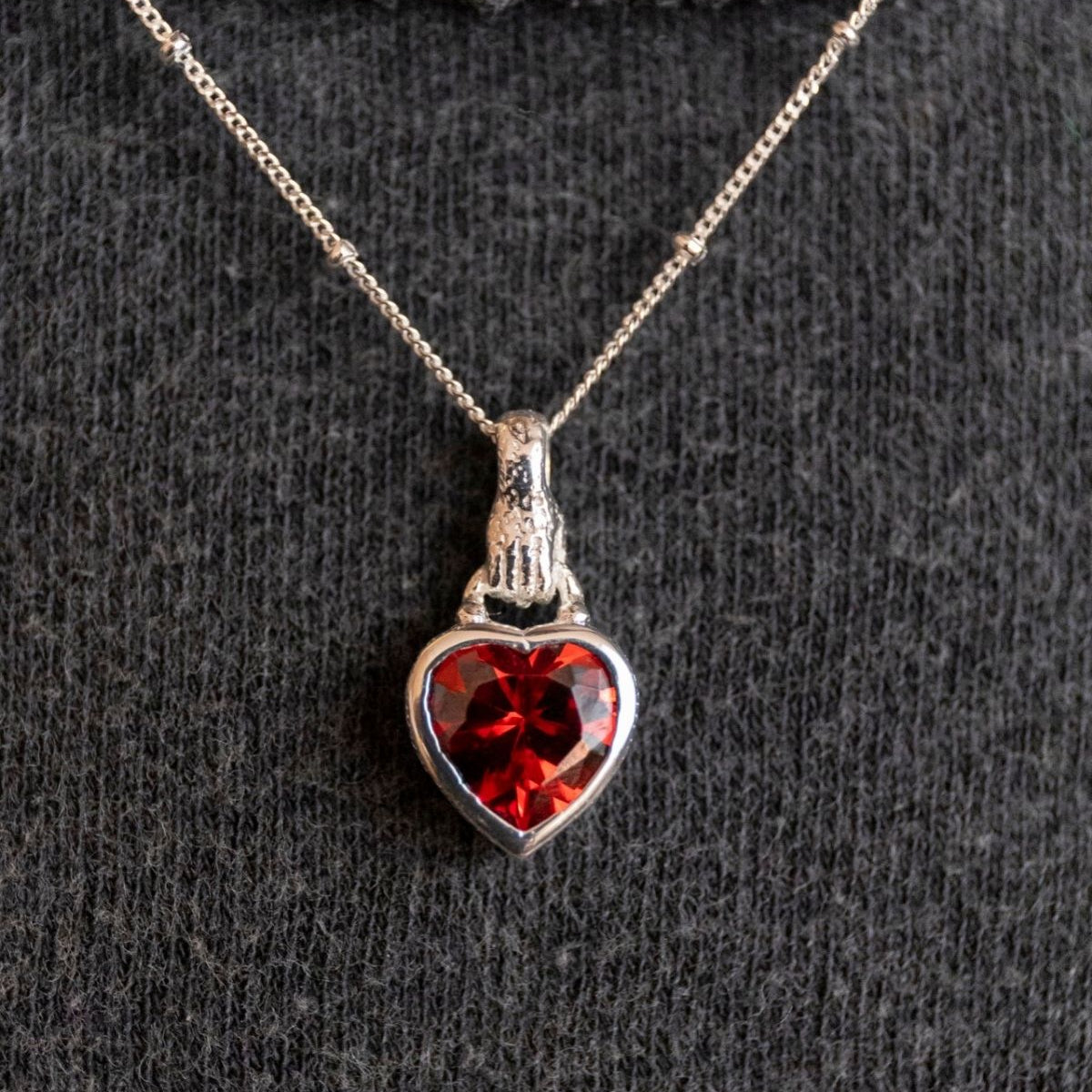 model wears Silver garnet hand in heart necklace on rolo chain