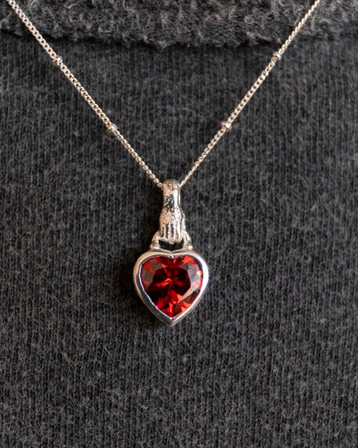 model wears Silver garnet hand in heart necklace on rolo chain