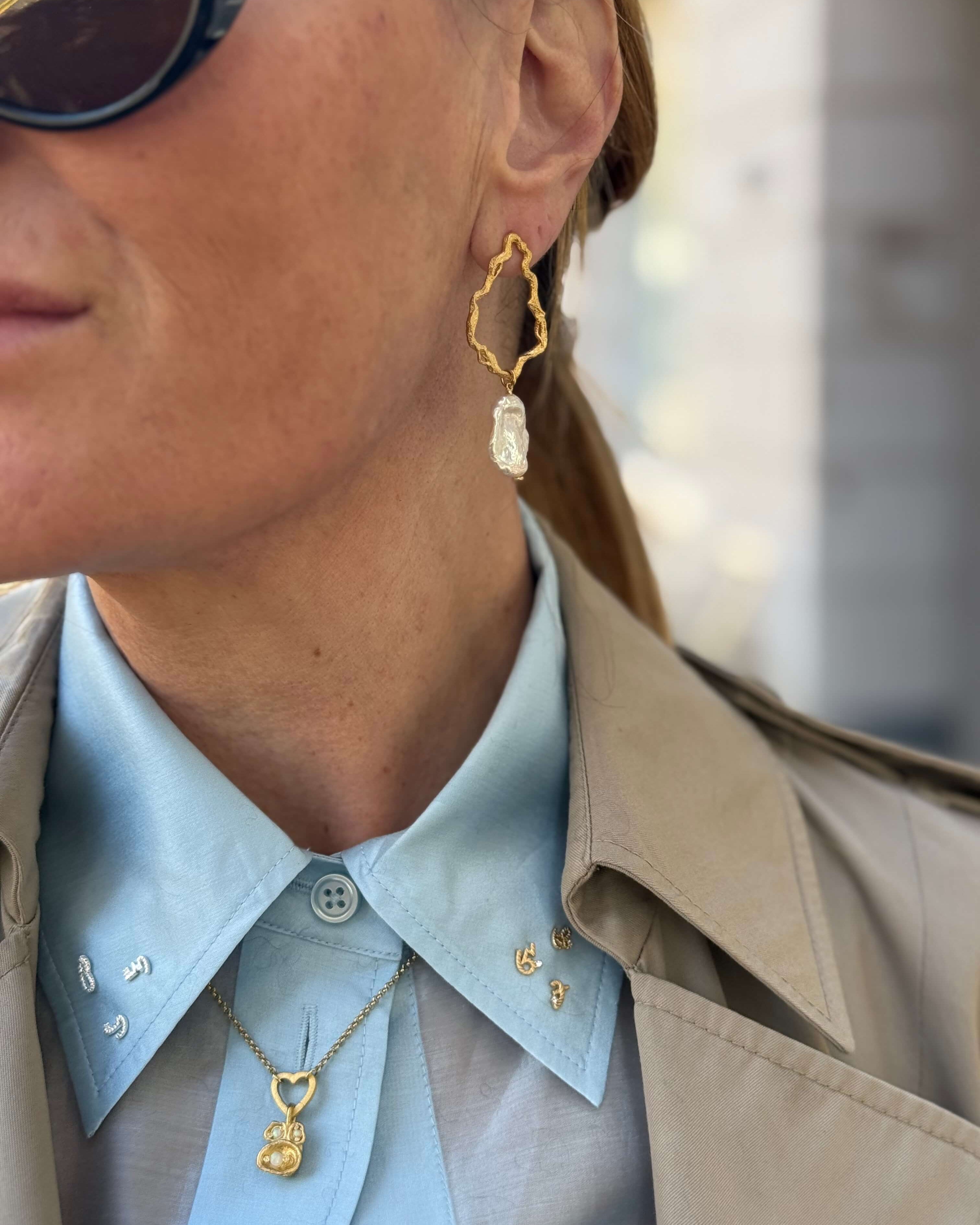 Woman in her 40s wears large gold pearl hoop earrings