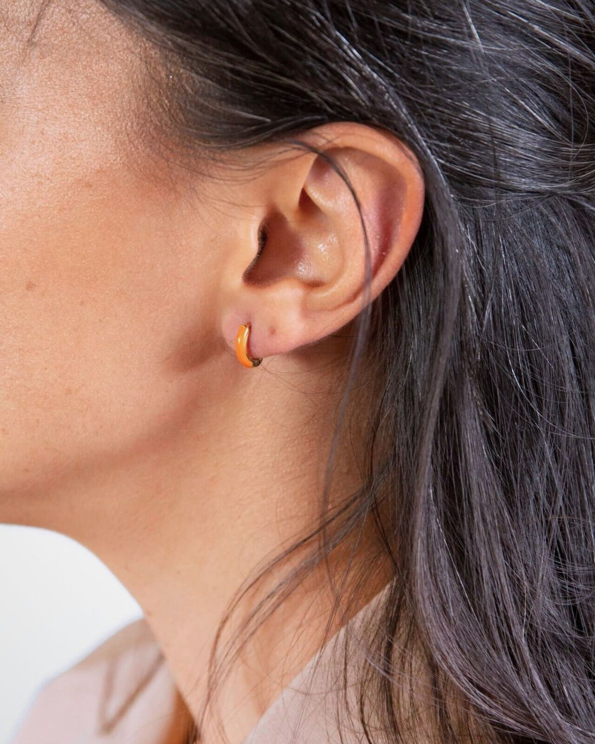 model wears Coral Gold Enamel Huggie Earrings