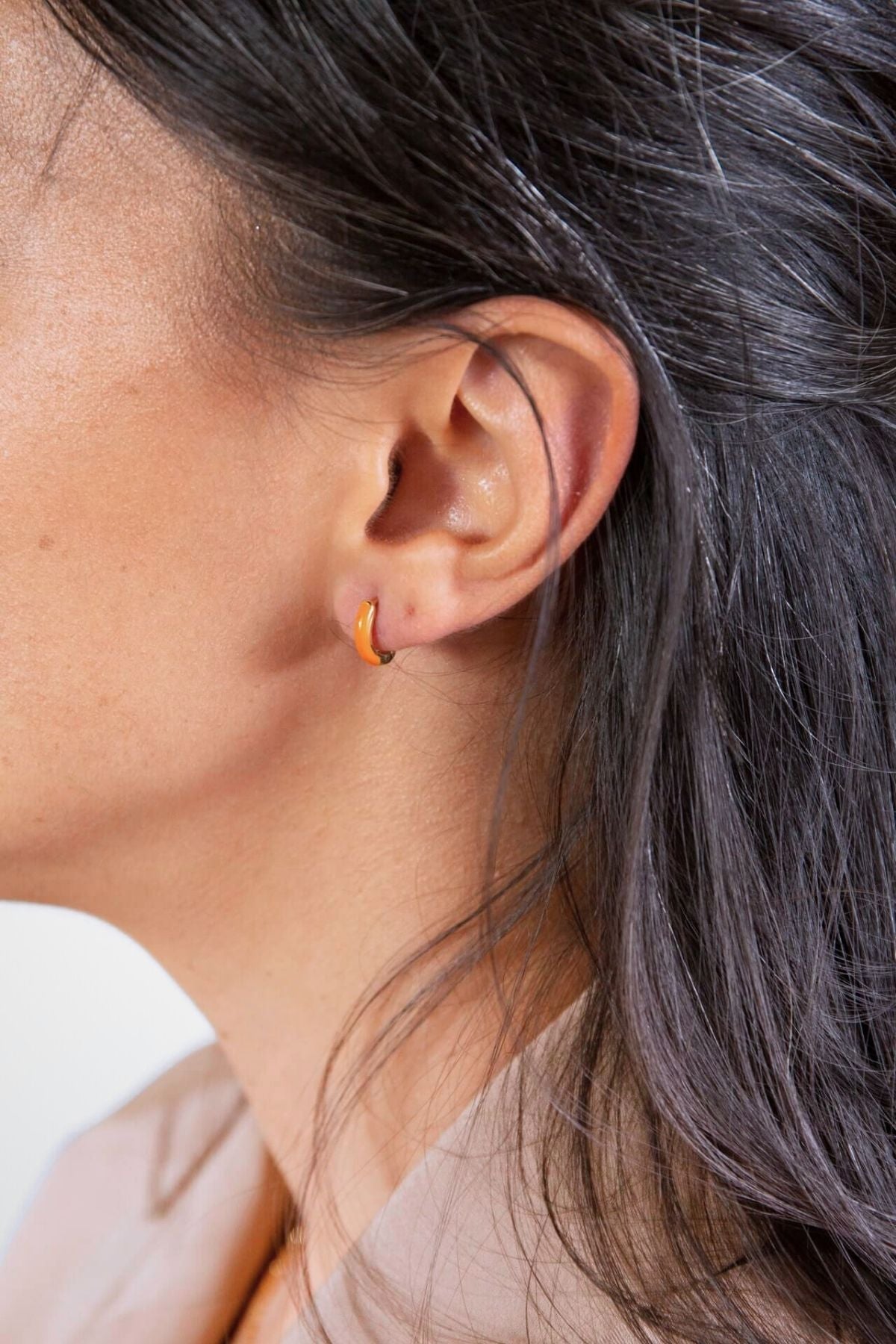model wears Coral Gold Enamel Huggie Earrings