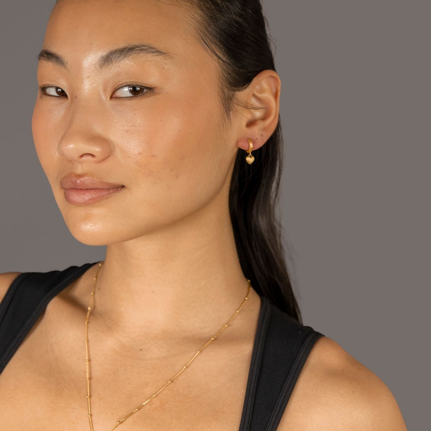 Jade wears Brushed Heart Gold Huggie Hoops
