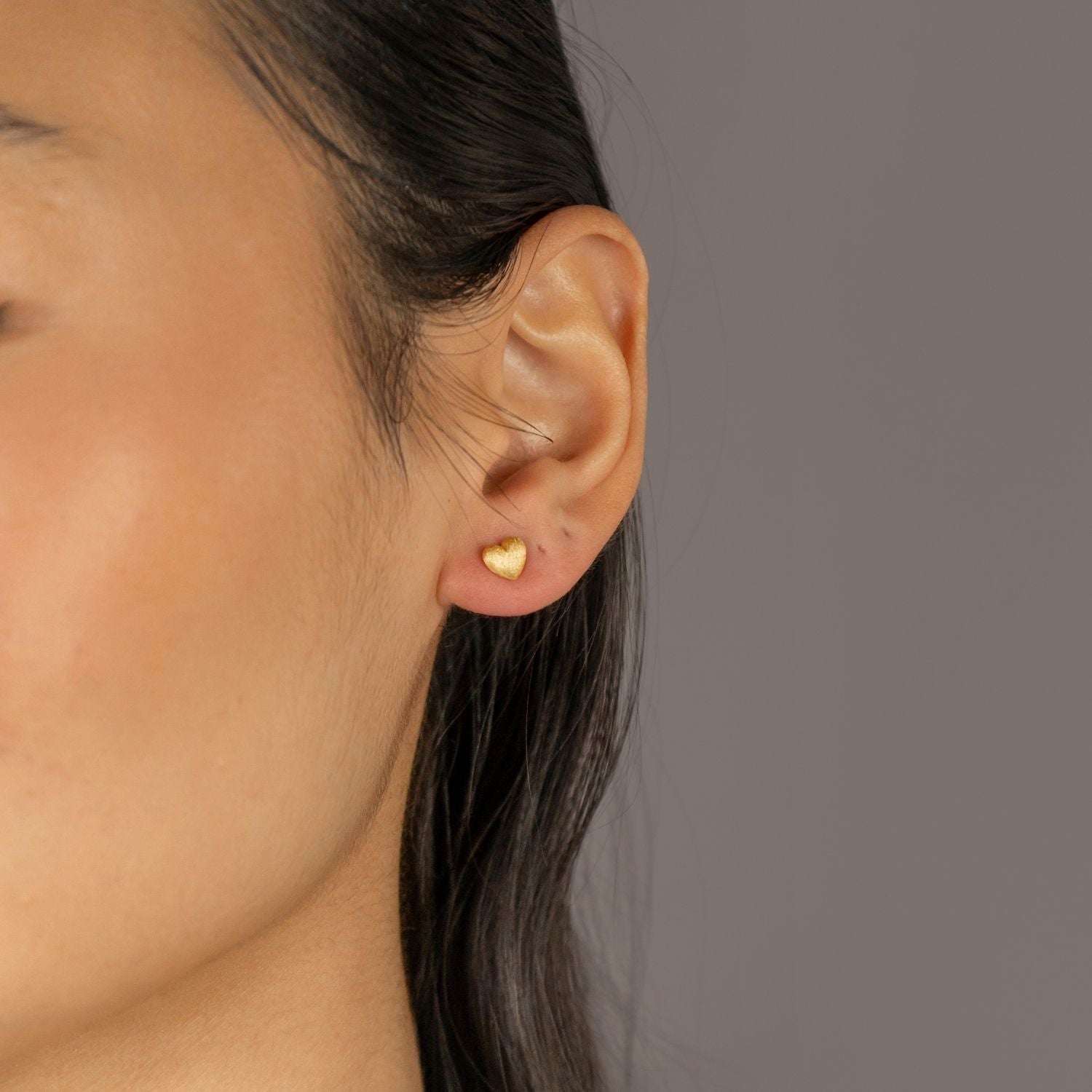 Jade wears Brushed Heart Gold Stud Earrings