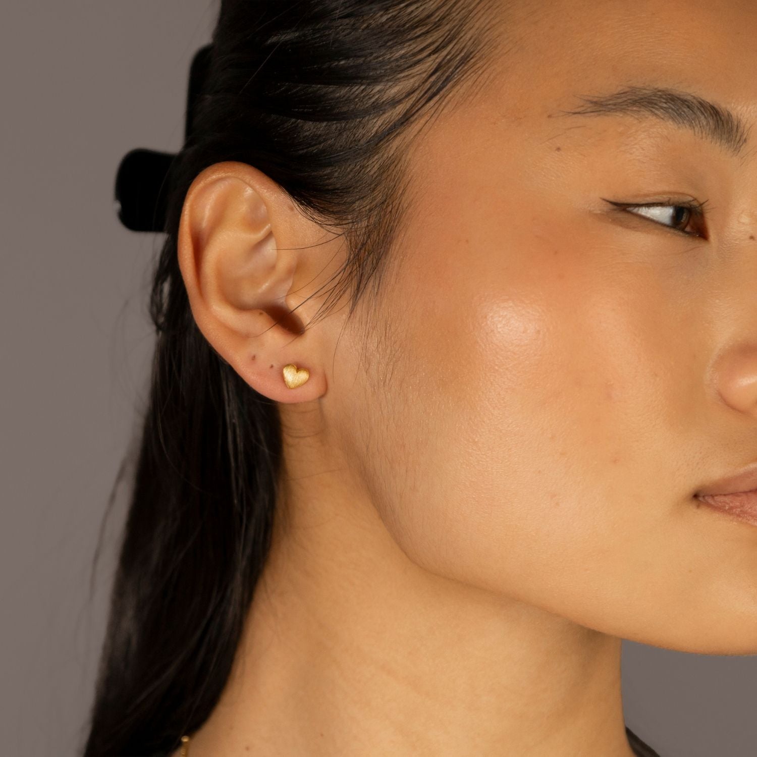 Jade wears Brushed Heart Gold Stud Earrings