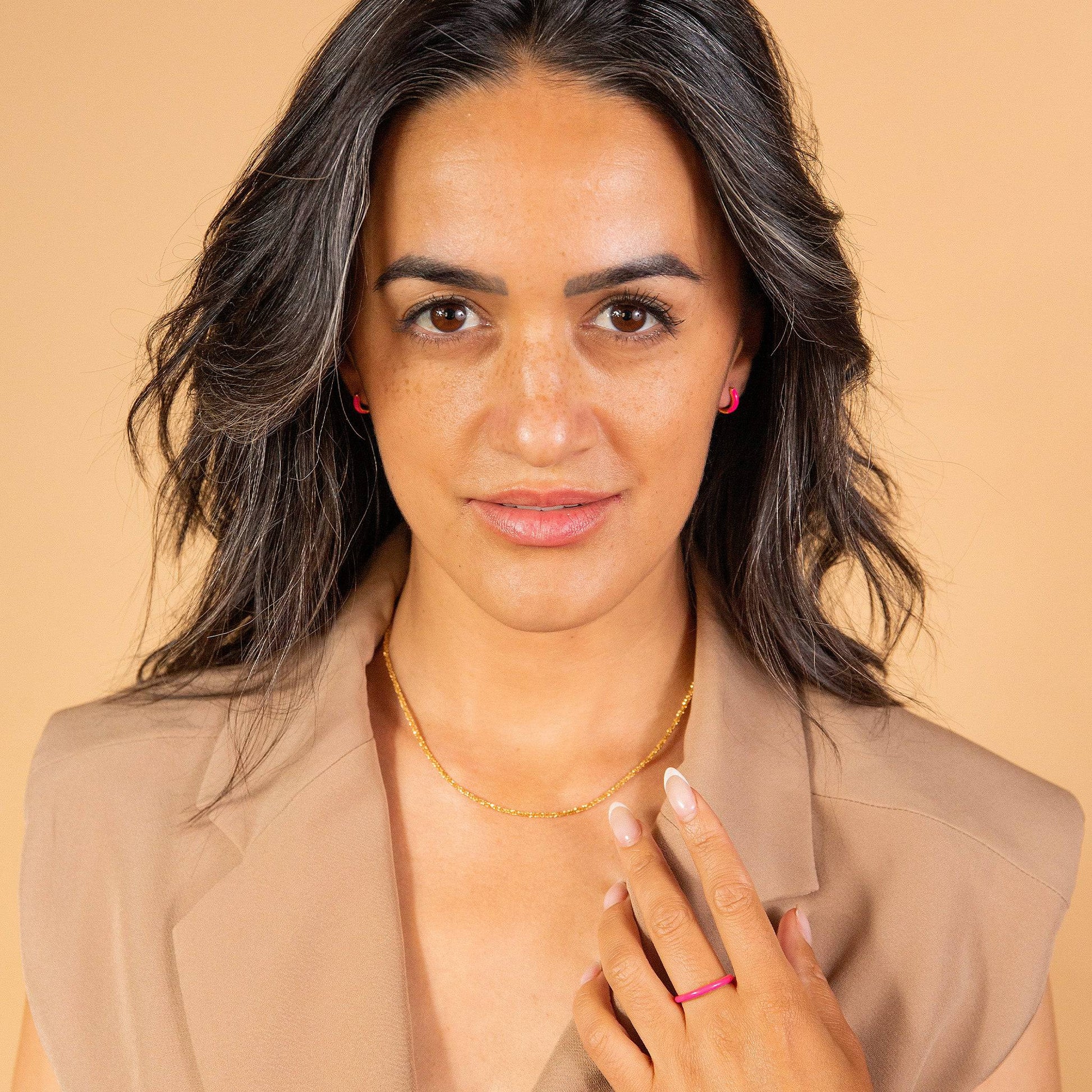 model wears Hot Pink Enamel Stacking Ring and pink enamel huggie hoop earrings