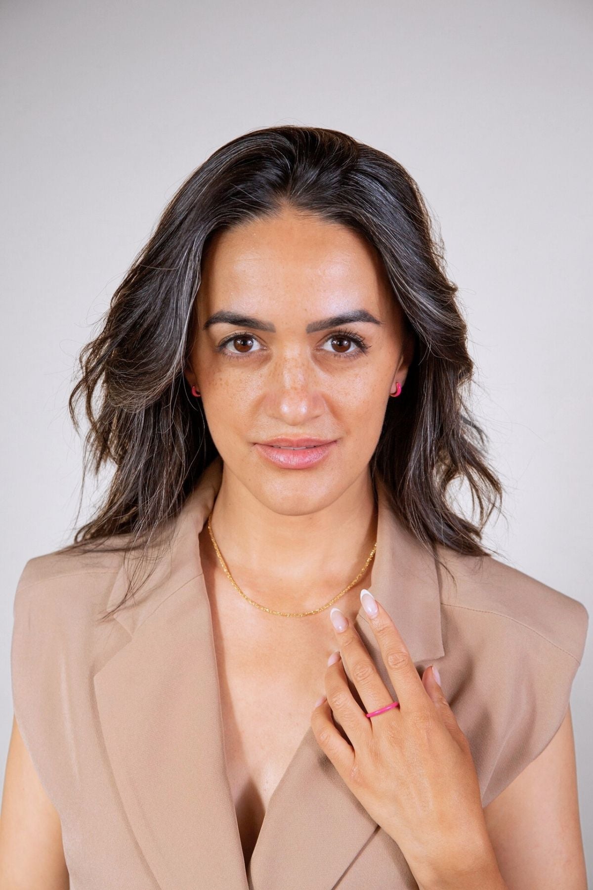model wears pink enamel ring and pink enamel huggie hoop earrings