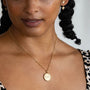 model-wears-14k-gold-vermeil-love-is-love-shorthand-coin-disc-necklace-claire-hill-designs-3