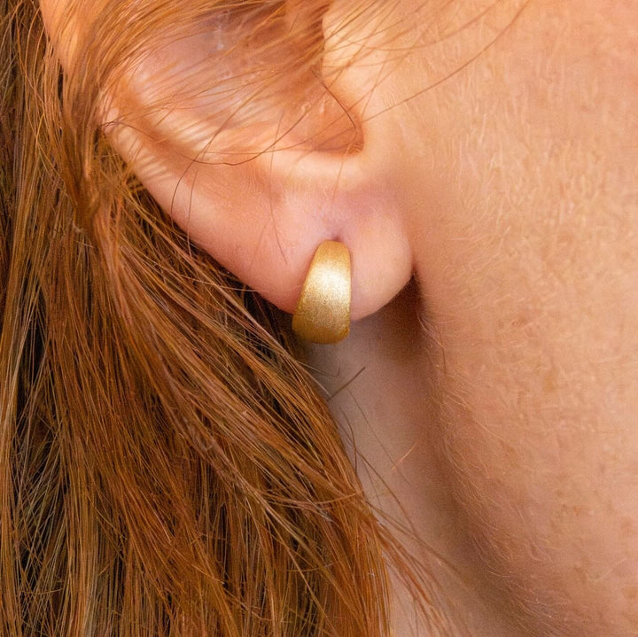 model wears Brushed Gold Chunky Huggie Hoops