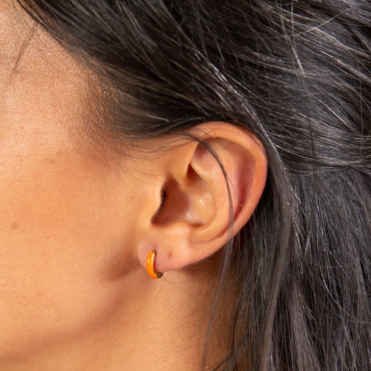 model wears Coral enamel and 18k gold vermeil huggie hoop earrings