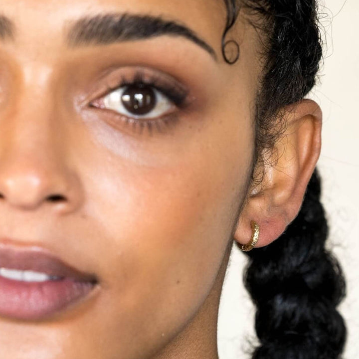 model-wears-18k-gold-vermeil-antique-textured-huggie-hoop-earrings-claire-hill-designs-close-up