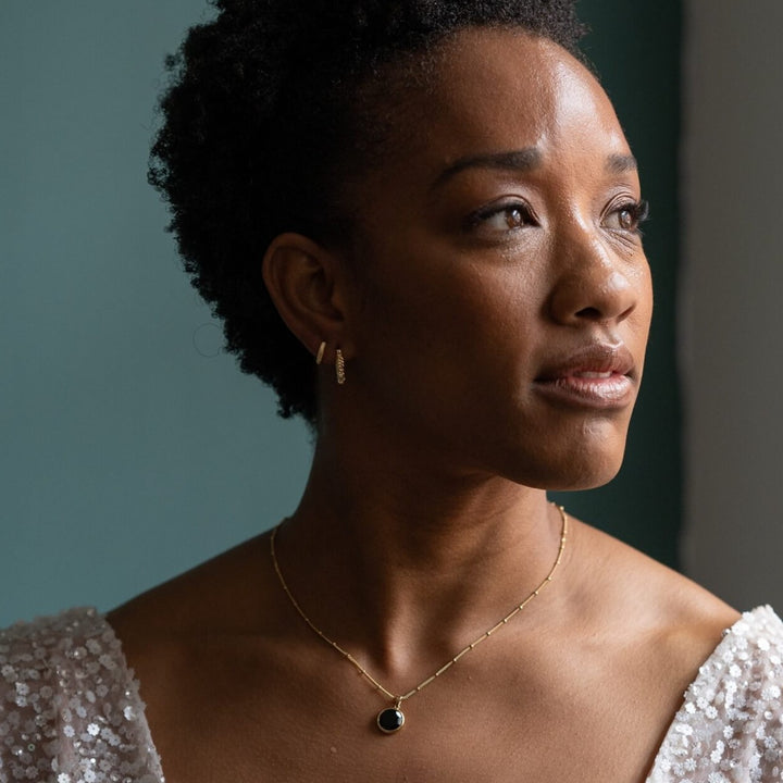 model wears 18k gold vermeil black onyx disc pendant necklace and 18k gold vermeil chunky hoop earrings