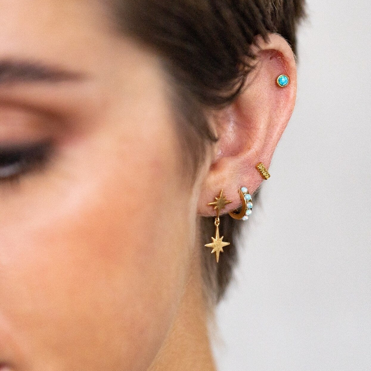 model wears 18k gold vermeil double north star stud earrings and a gold ear stack of huggie hoop earrings and stud earrings