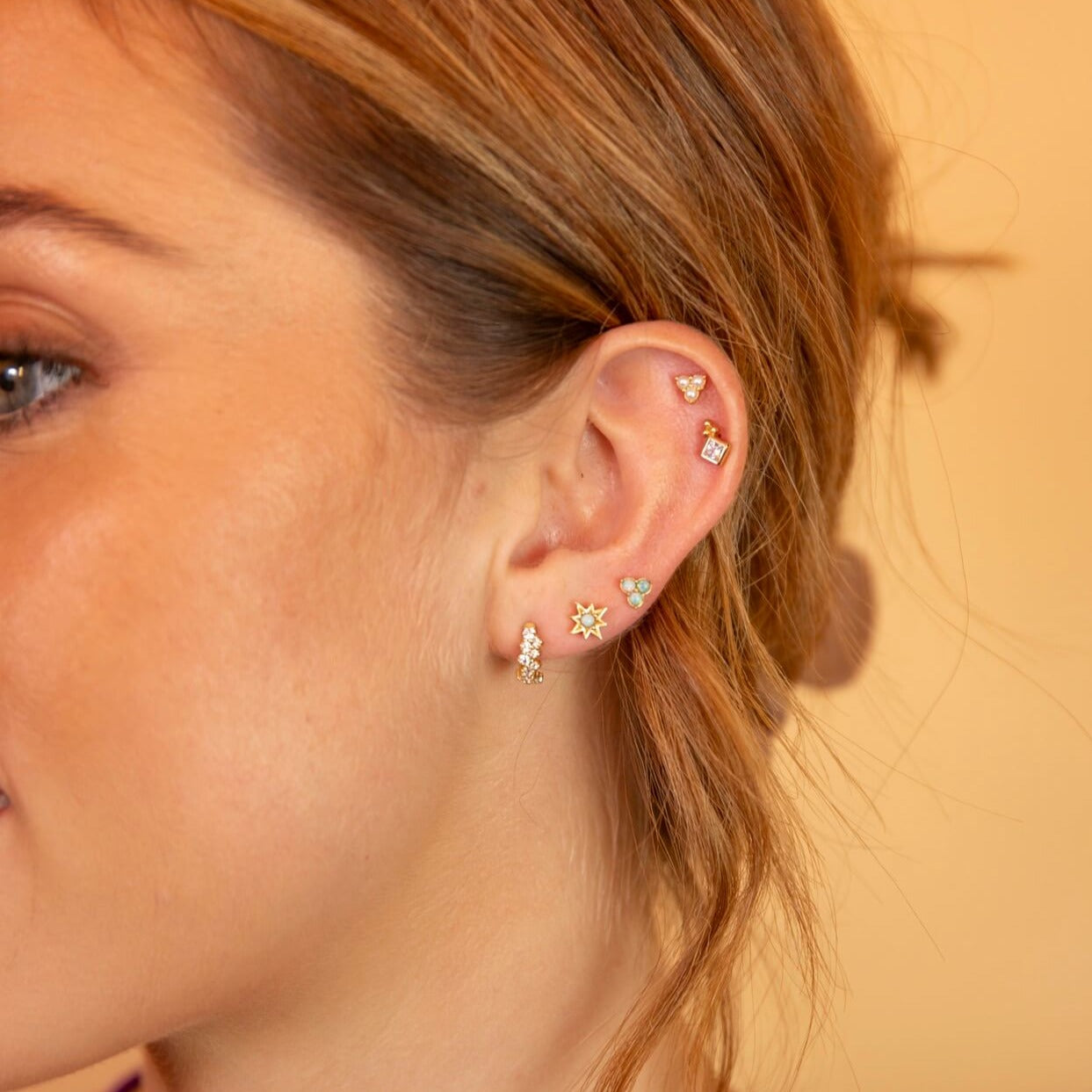 model wears Galaxy Sparkly Gold Scatter Huggie Hoop Earrings and studs - curated ear stack