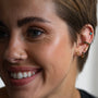 model wears gold ear stack of studs and huggie hoop earrings including 18k gold vermeil brushed north star stud earrings