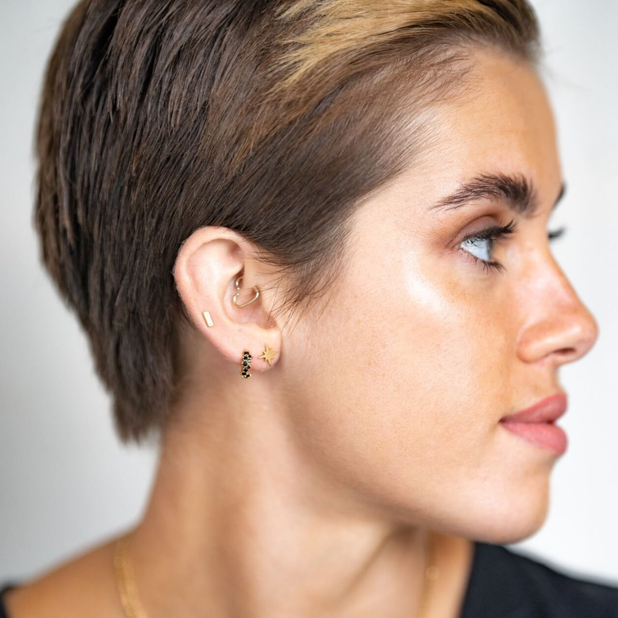 model wears 18k gold vermeil north star stud earrings and black and gold scatter gemstone huggie hoop earrings