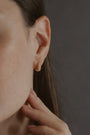 model wears Pearl Antique Gold Huggie Hoop Earrings
