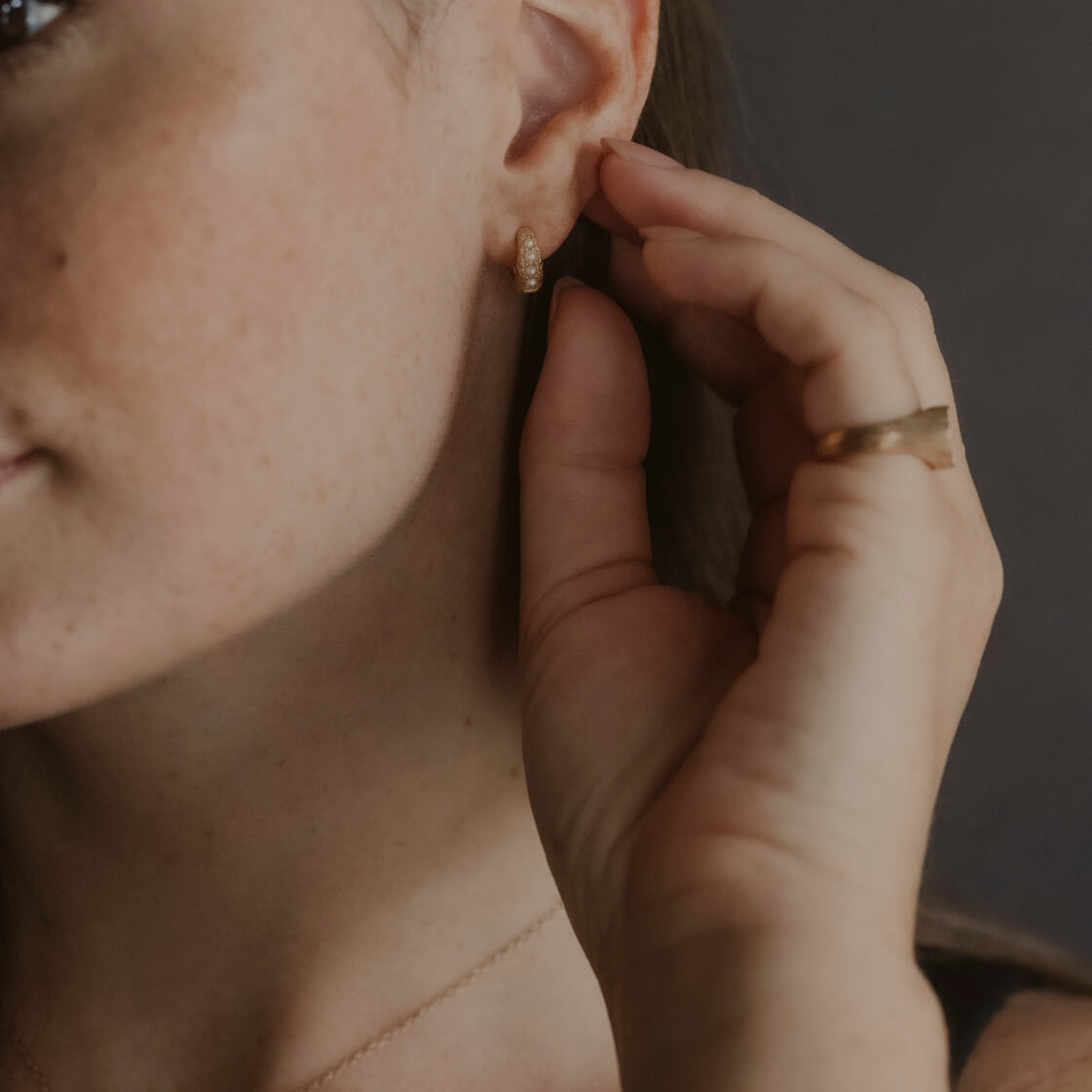 model wears Pearl Antique Gold Huggie Hoop Earrings
