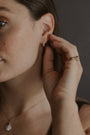 model wears Pearl Antique Gold Huggie Hoop Earrings
