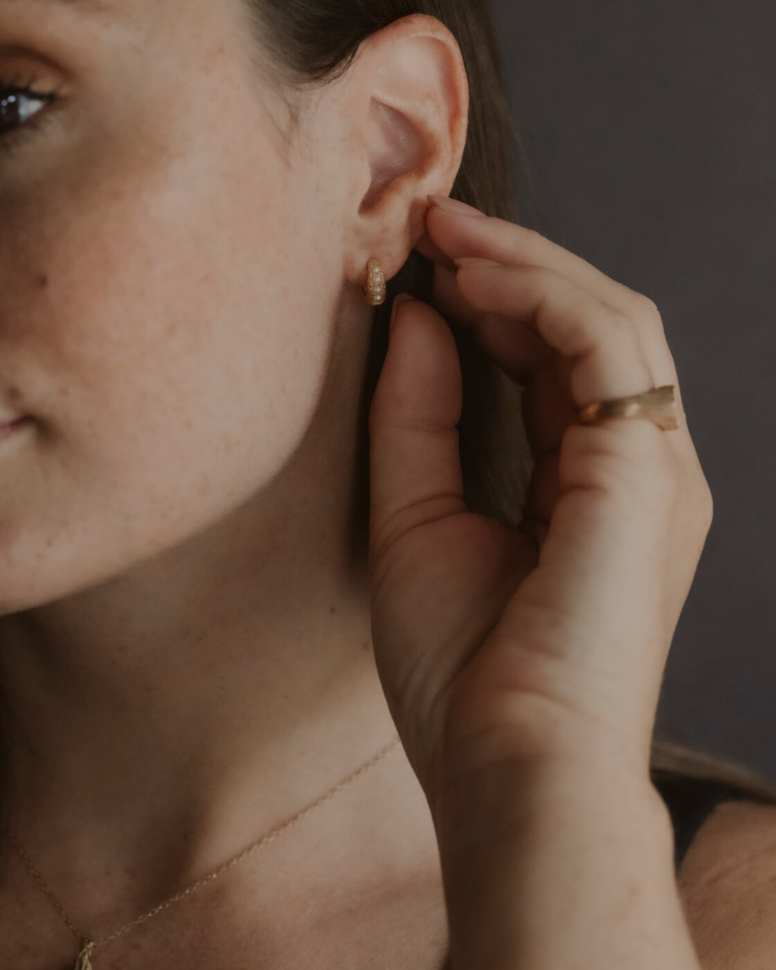 model wears Pearl Antique Gold Huggie Hoop Earrings
