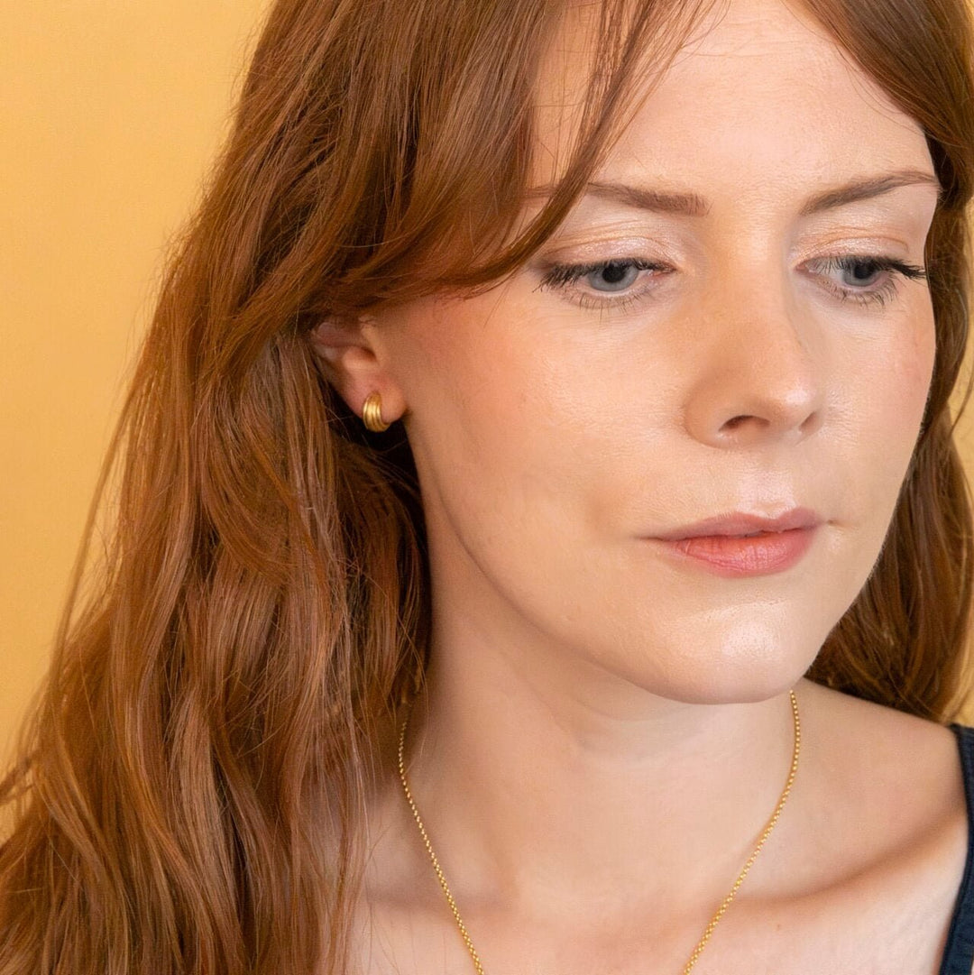model wears chunky 18k gold vermeil ridged huggie hoop earrings