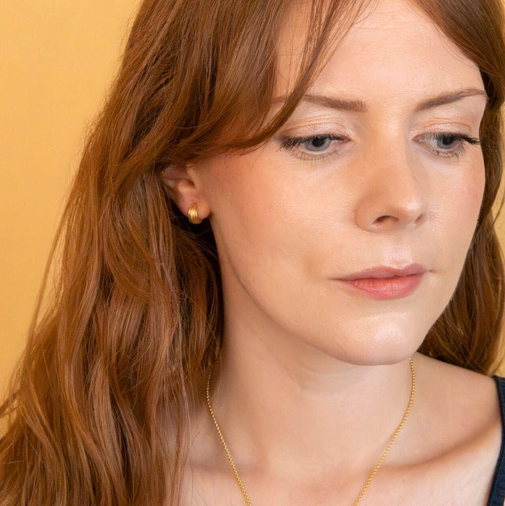 model wears chunky 18k gold vermeil ridged huggie hoop earrings