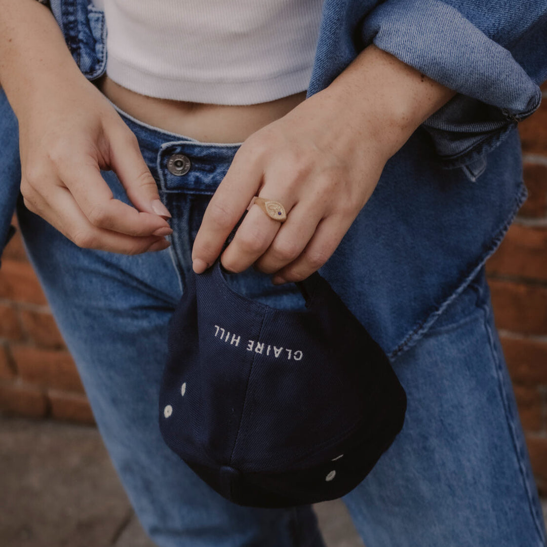 Model holds navy Claire Hill embroidered baseball cap