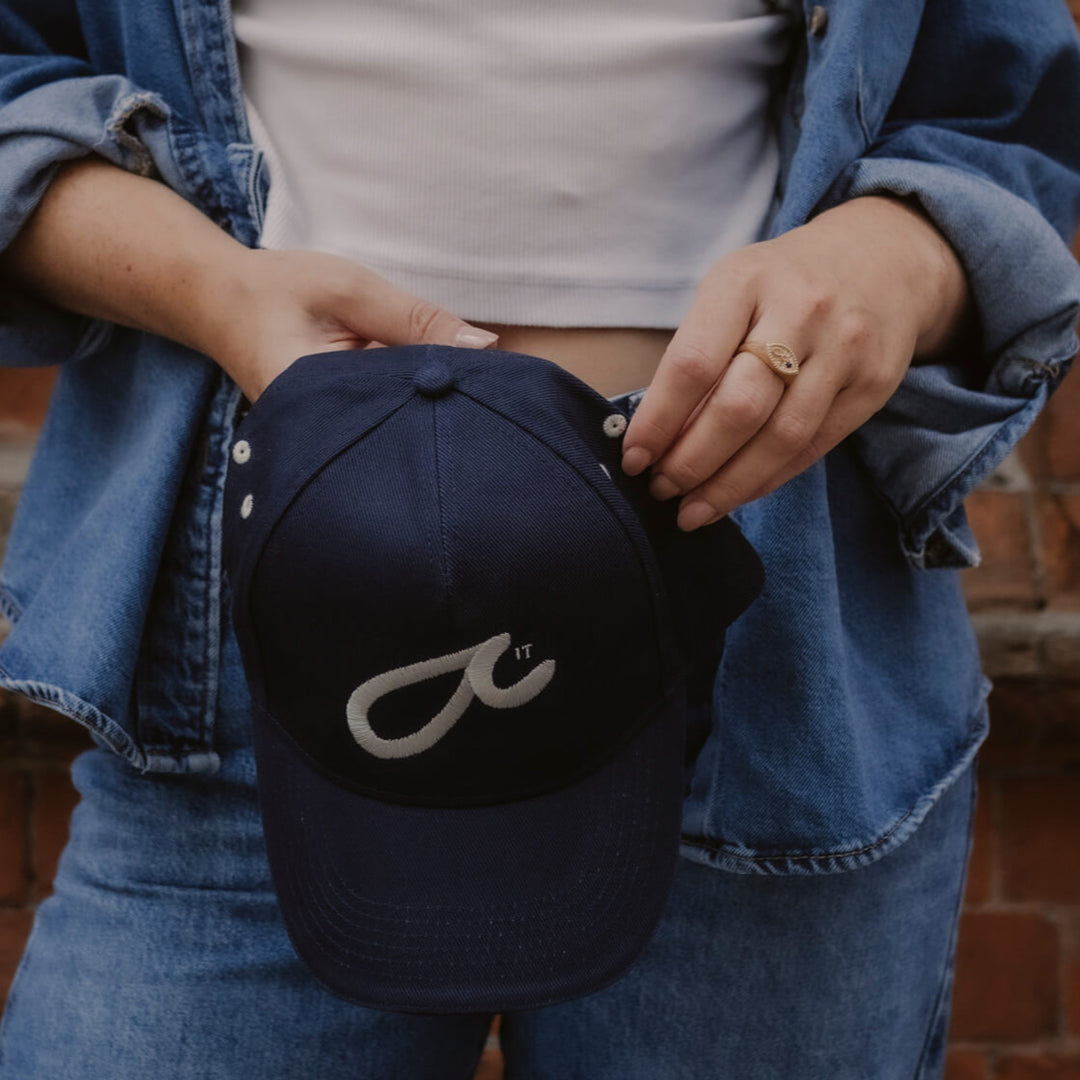 Model holds navy Fuck It Shorthand embroidered baseball cap