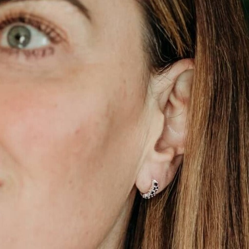 model wears black cubic zirconia and silver huggie hoop earrings