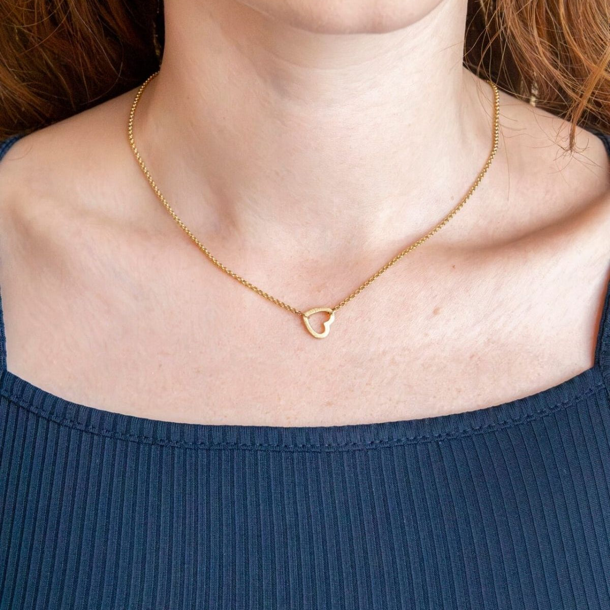 model wears brushed heart connector necklace 
