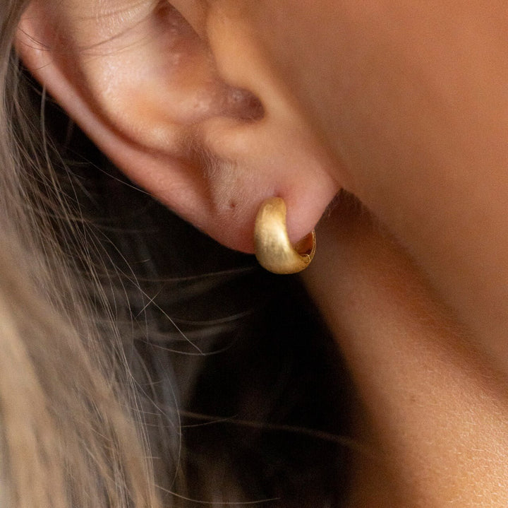 model wears Brushed Gold Chunky Huggie Hoops
