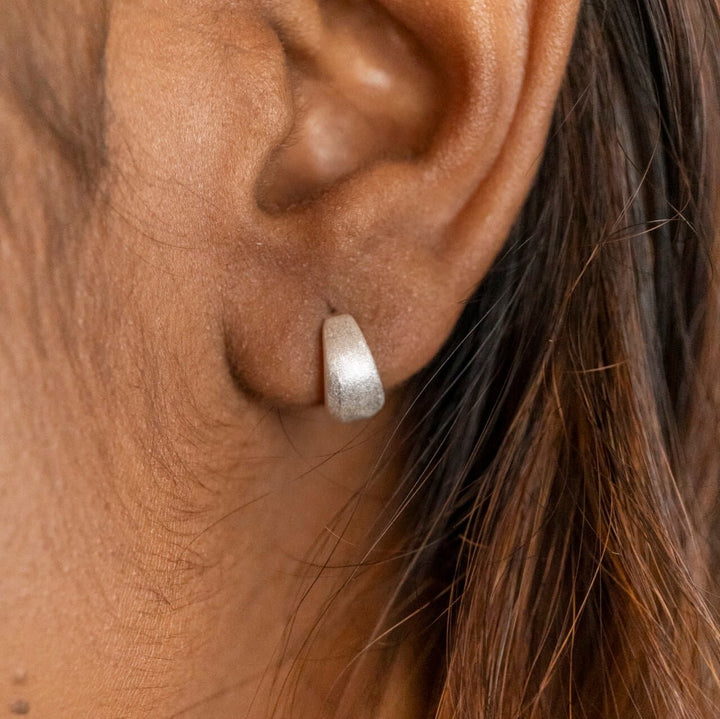 model wears chunky silver huggie hoop earrings