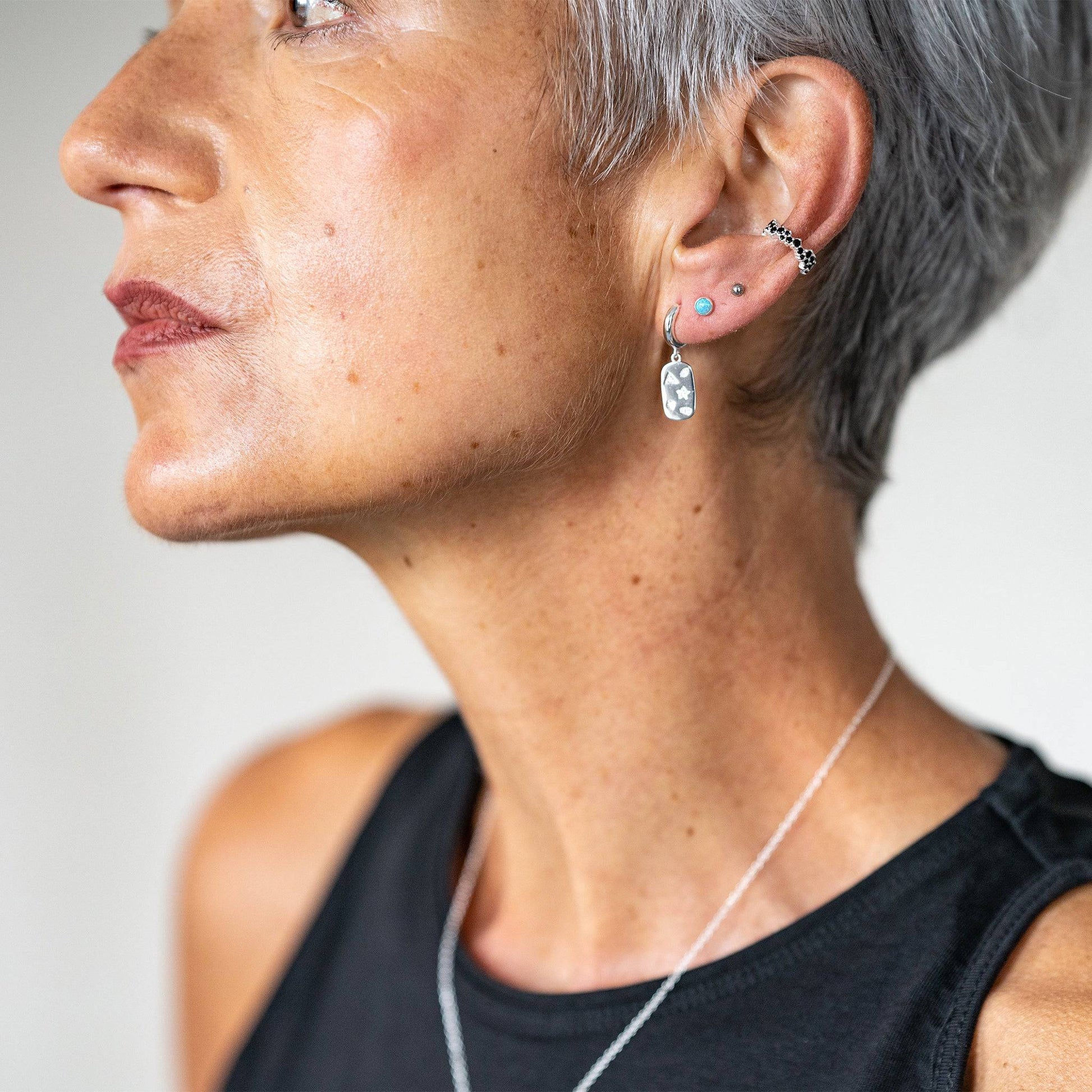model wears Mystic Star Silver Dog Tag Huggie Earrings