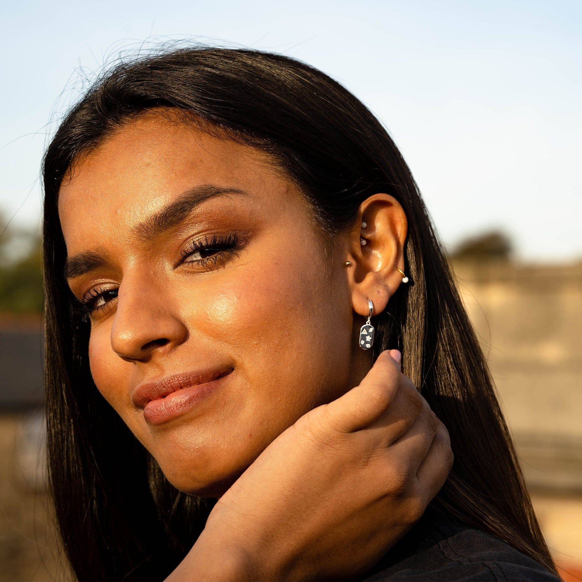 model wears Mystic Star Silver Dog Tag Huggie Earrings