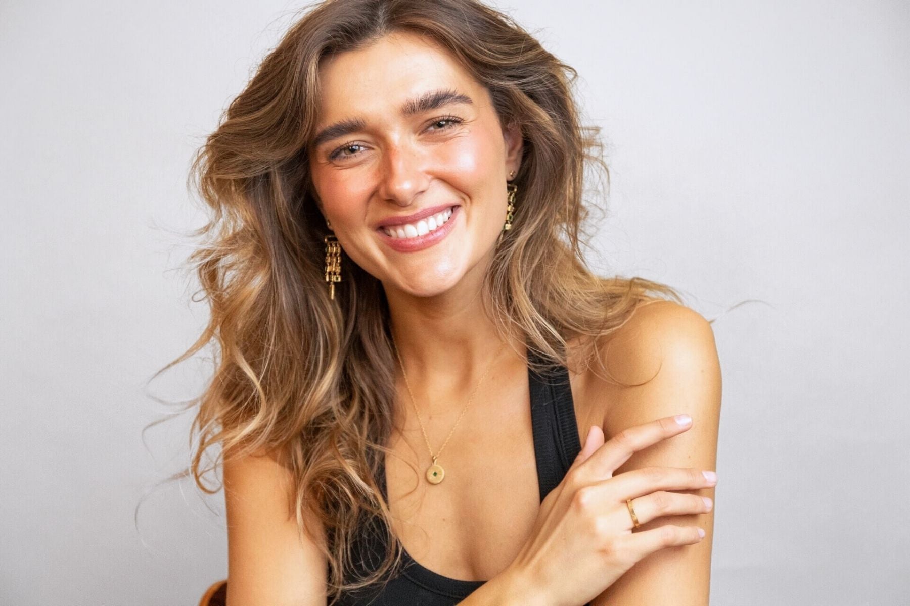 model wears emerald gold chandelier ear jacket earrings and gold lovespoon charm necklace