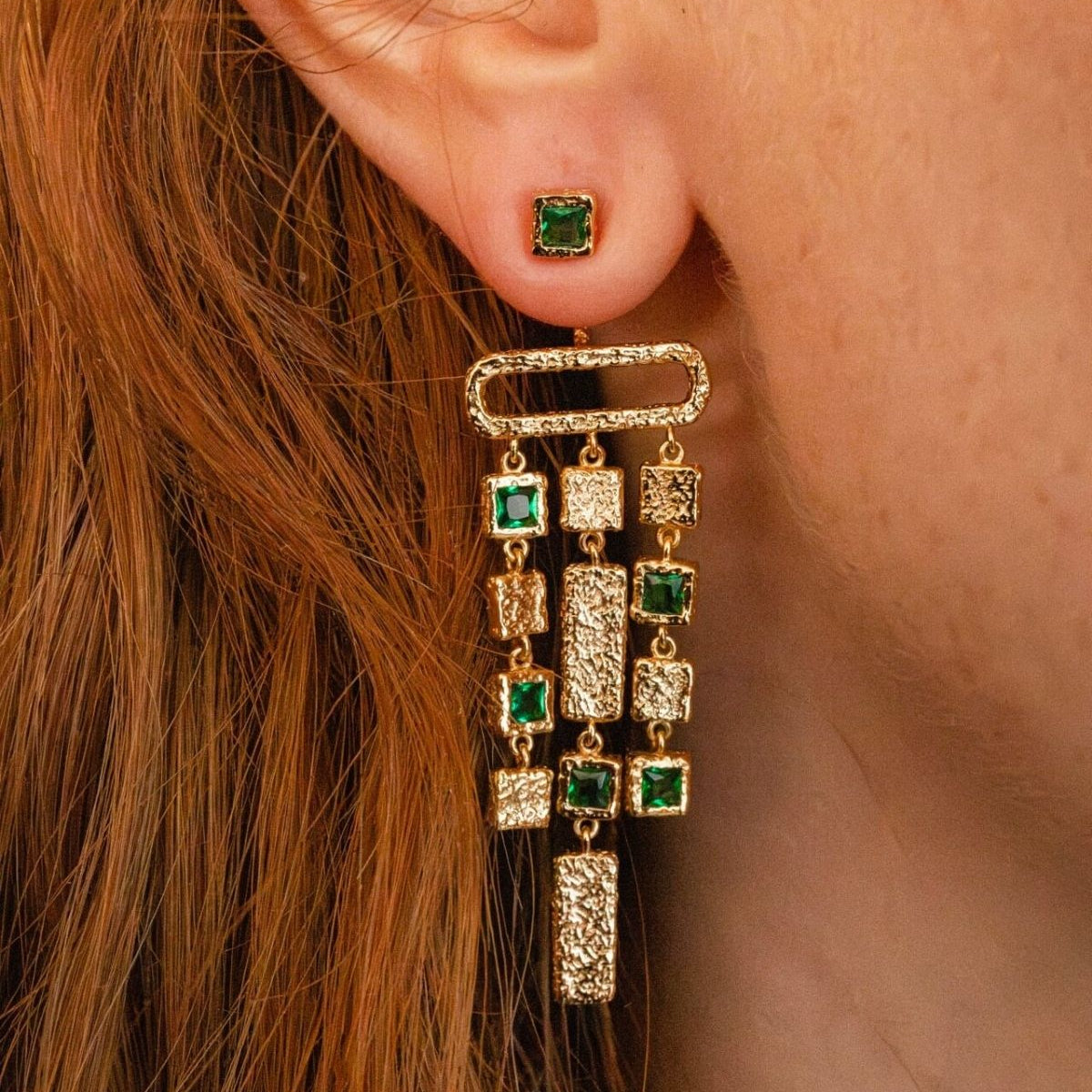 model wears emerald gold chandelier ear jacket earrings