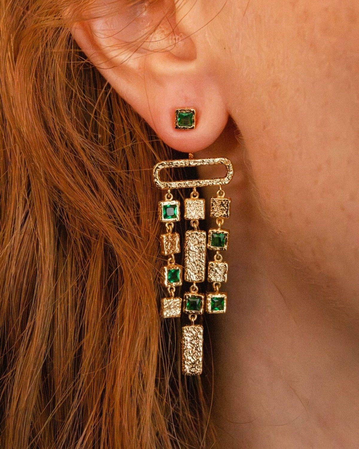 model wears emerald gold chandelier ear jacket earrings