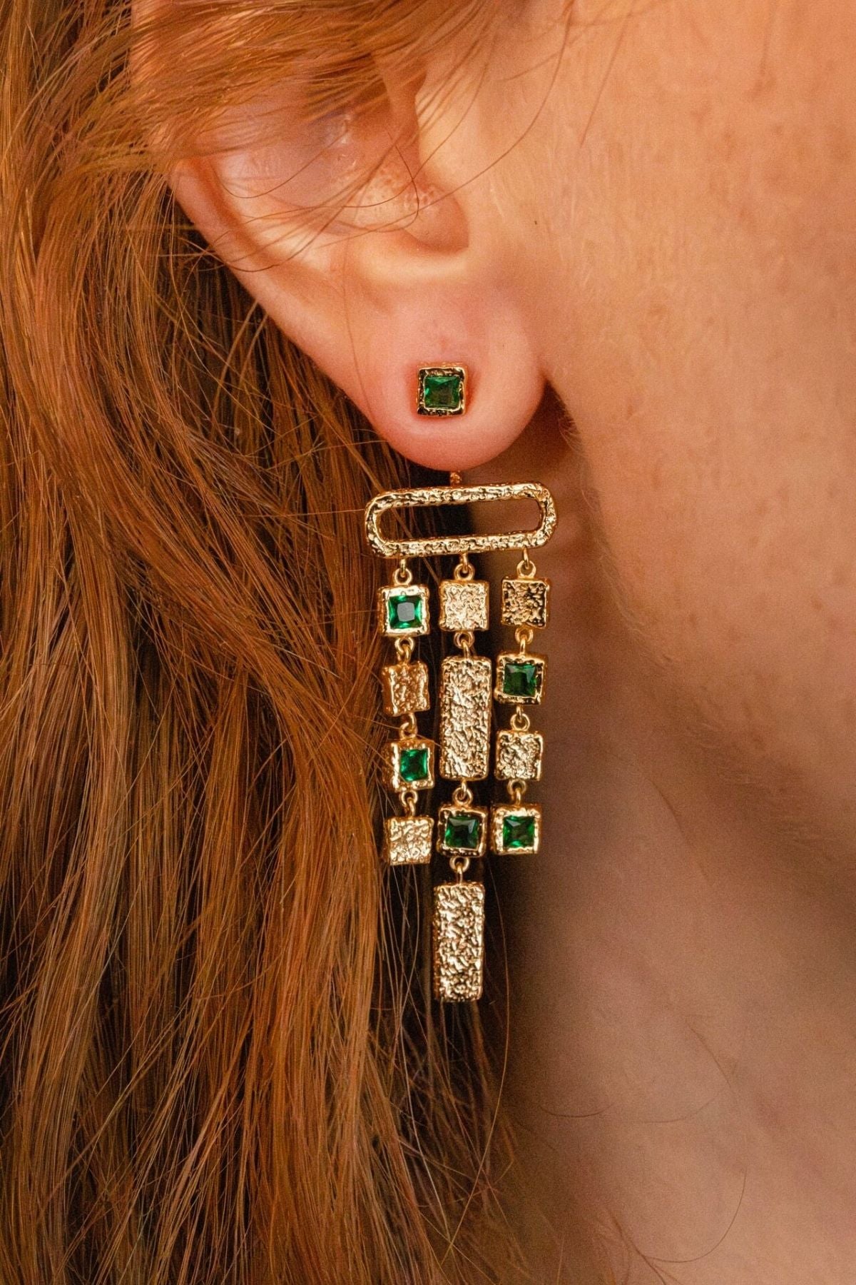 model wears emerald gold chandelier ear jacket earrings